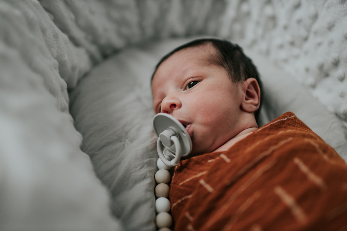 a baby laying in a crib with a pacifier in it's mouth related to Embrace Calming Neutrality for Your Little One: Discover Neutral Baby Bedding