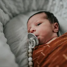 a baby laying in a crib with a pacifier in it's mouth related to Embrace Calming Neutrality for Your Little One: Discover Neutral Baby Bedding