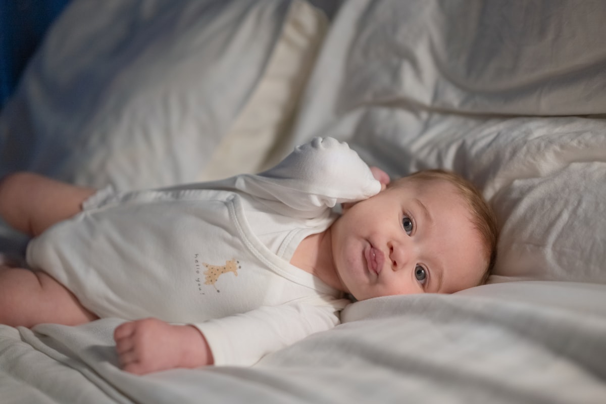 A baby laying on a bed with white sheets related to Gently Does It: Bringing the Forest to Your Little Buck