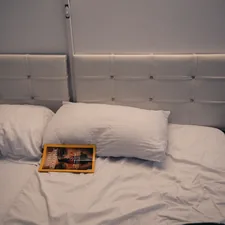 A bed is made with white pillows and sheets. related to The Elegance of White Leather Bed Design