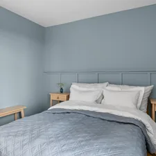 A bed sitting in a bedroom next to a window related to French Blue Bedding: A Touch of Parisian Elegance