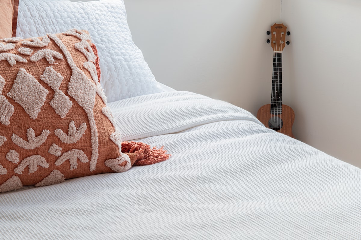 a bed with a white comforter and a guitar on the wall related to Tapestry Coverlet Bedding