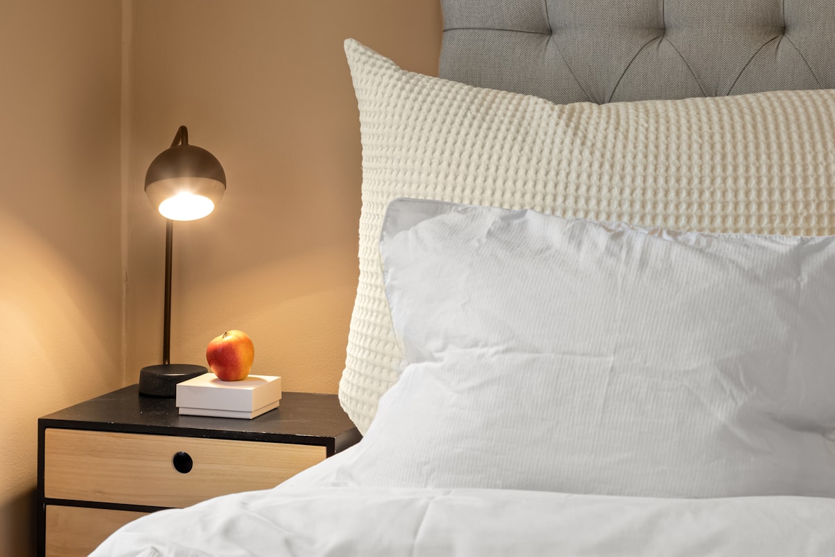 A bed with a white comforter and a night stand related to Oversized King Coverlet: The Perfect Comforter for Your Bed