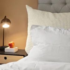 A bed with a white comforter and a night stand related to Oversized King Coverlet: The Perfect Comforter for Your Bed