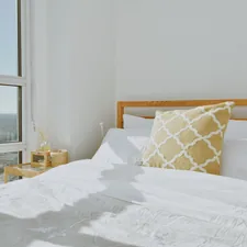 a bed with a white comforter and a yellow pillow related to Brighten Up Your Bedroom with a Yellow Coverlet for Your King-Sized Bed