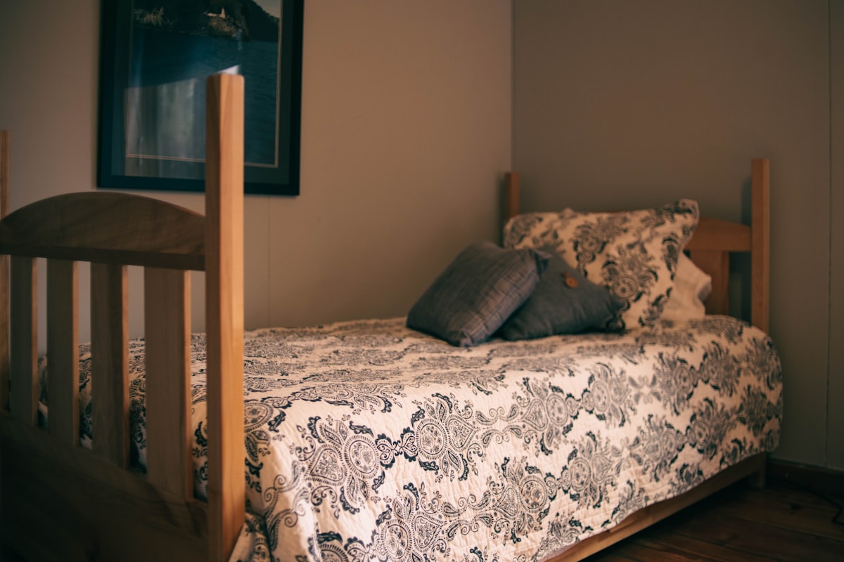 a bed with a wooden headboard and a picture on the wall related to Embrace Cozy Comfort: Exploring the Ultimate Twin Size Bed Experience