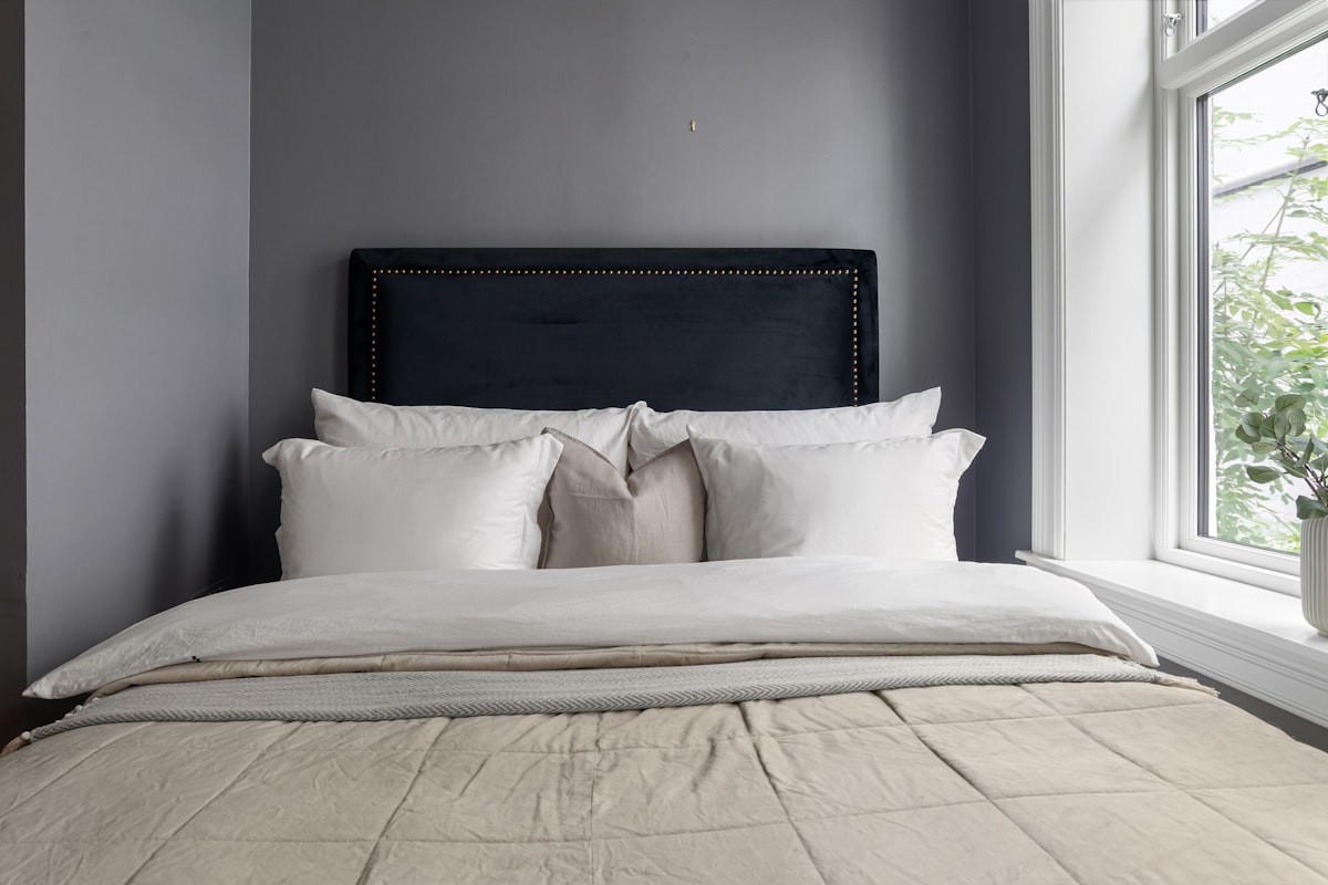 A bed with white pillows and a black headboard related to Oversized King Coverlet: The Perfect Comforter for Your Bed