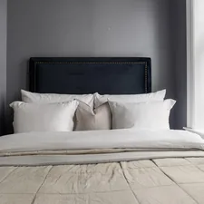 A bed with white pillows and a black headboard related to Oversized King Coverlet: The Perfect Comforter for Your Bed
