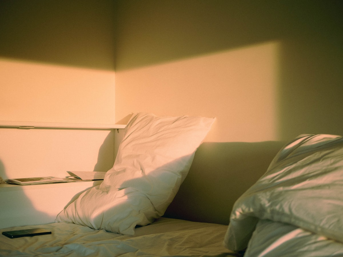 a bed with white sheets and pillows in a room related to Elevate Your Sleeping Experience: Make Your Bed Higher