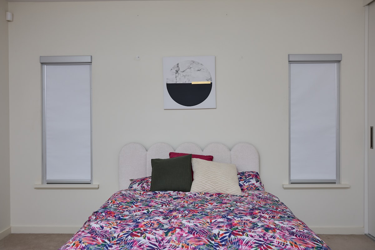 A bedroom with a bed, floral duvet, and abstract art. related to Transforming Your Home with Bed Bath & Beyond Blinds