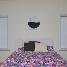 A bedroom with a bed, floral duvet, and abstract art. related to Transforming Your Home with Bed Bath & Beyond Blinds