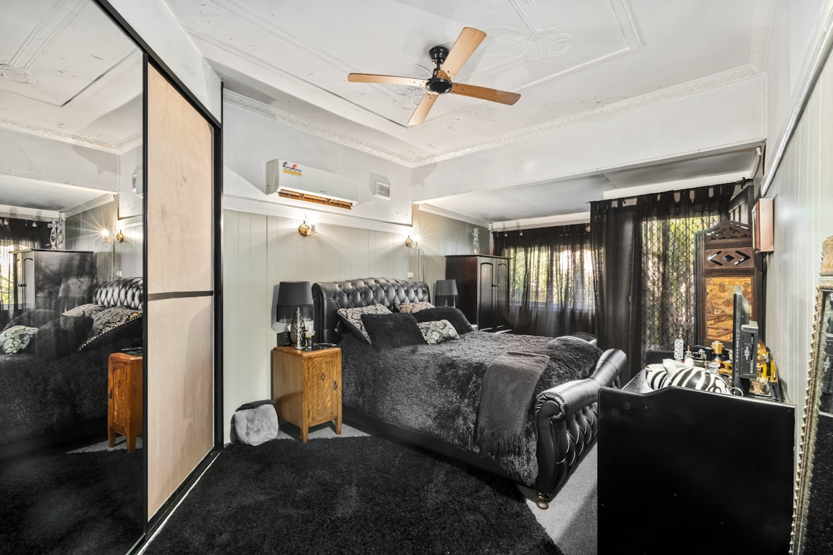 A bedroom with a large bed and a ceiling fan related to The Mirrored Queen Bed: A Reflection of Elegance and Luxury
