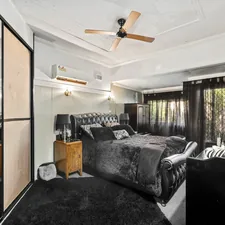 A bedroom with a large bed and a ceiling fan related to The Mirrored Queen Bed: A Reflection of Elegance and Luxury