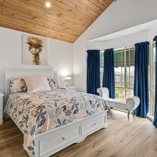A bedroom with a large bed and a wooden ceiling related to Maximizing Space: A Comprehensive Guide to Queen Beds with Drawers
