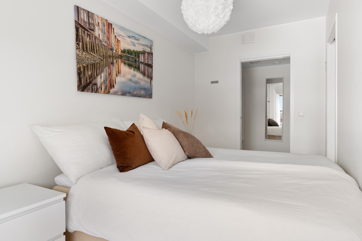 A bedroom with a white bed and a painting on the wall related to The Beauty of Twin Bed White