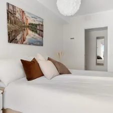 A bedroom with a white bed and a painting on the wall related to The Beauty of Twin Bed White