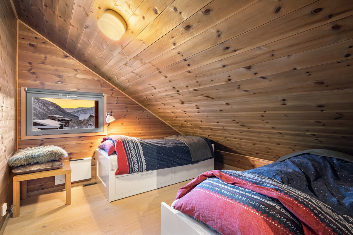 A bedroom with two beds in it and wooden walls related to The Ultimate Guide to Twin Loft Beds