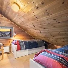 A bedroom with two beds in it and wooden walls related to The Ultimate Guide to Twin Loft Beds