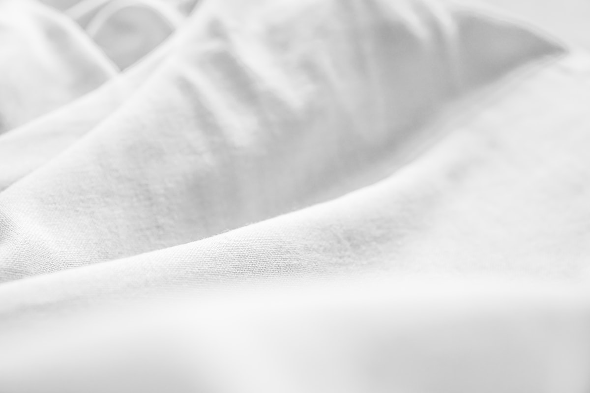 a black and white photo of a bed with white sheets related to Essential Bedding: White Coverlet King