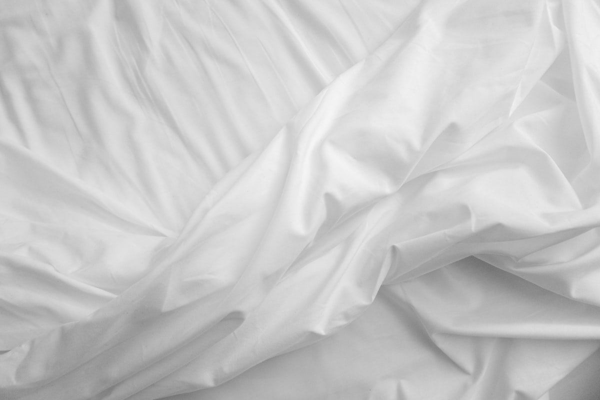 a black and white photo of a bed with white sheets related to White King Size Coverlet