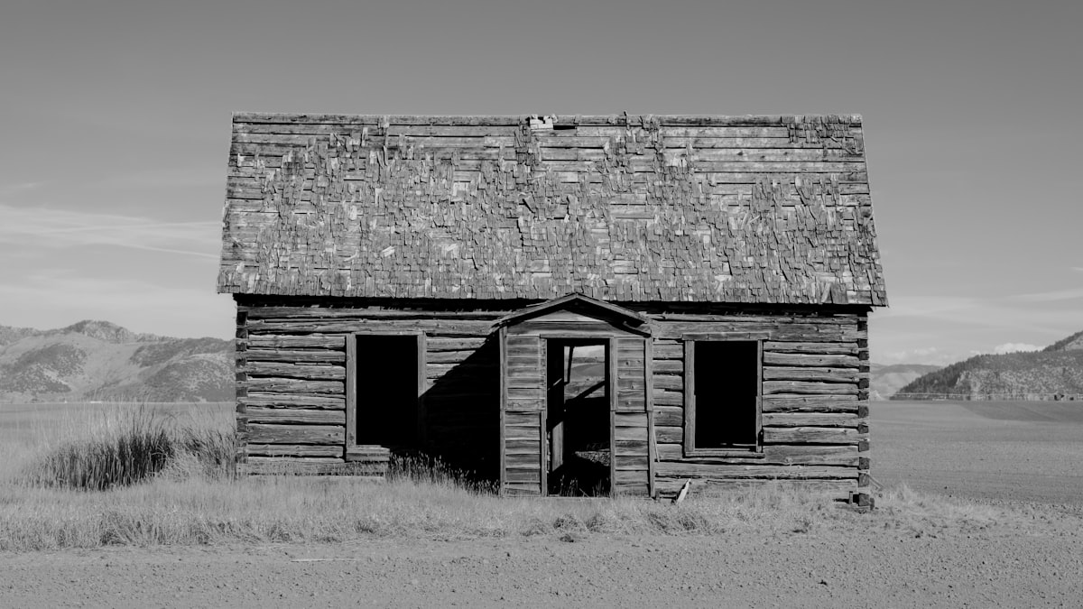 A black and white photograph of an abandoned homestead in an open field in rural Gem Valley, Idaho, USA, related to Western Window Valances: Add a Touch of Rustic Charm