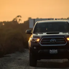 a black truck driving down a dirt road related to Maximizing Your Pickup's Potential: Tacoma Bed Extender Options