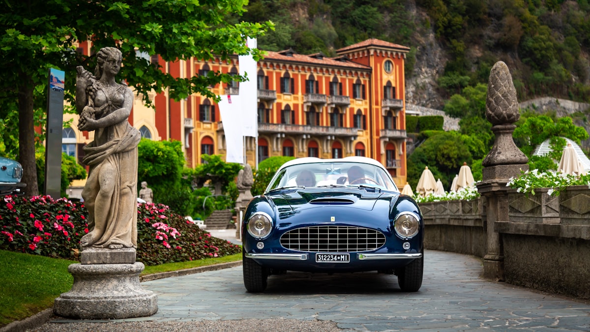 A blue car driving down a street next to a statue related to Embracing the Iconic Elegance of the Blue Rooster Chiminea