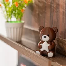 A brown 3D printed teddy bear by Snapmaker sits on a wooden shelf, holding a white star beside a flower pot. related to Charming Nursery Ideas with Cozy Bedding