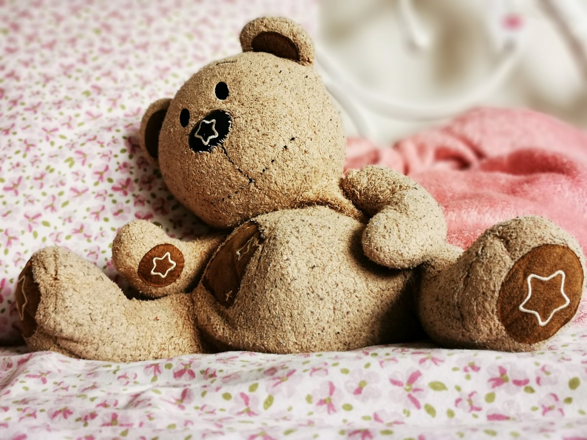 a brown teddy bear sitting on top of a bed related to Charming Nursery Ideas with Cozy Bedding
