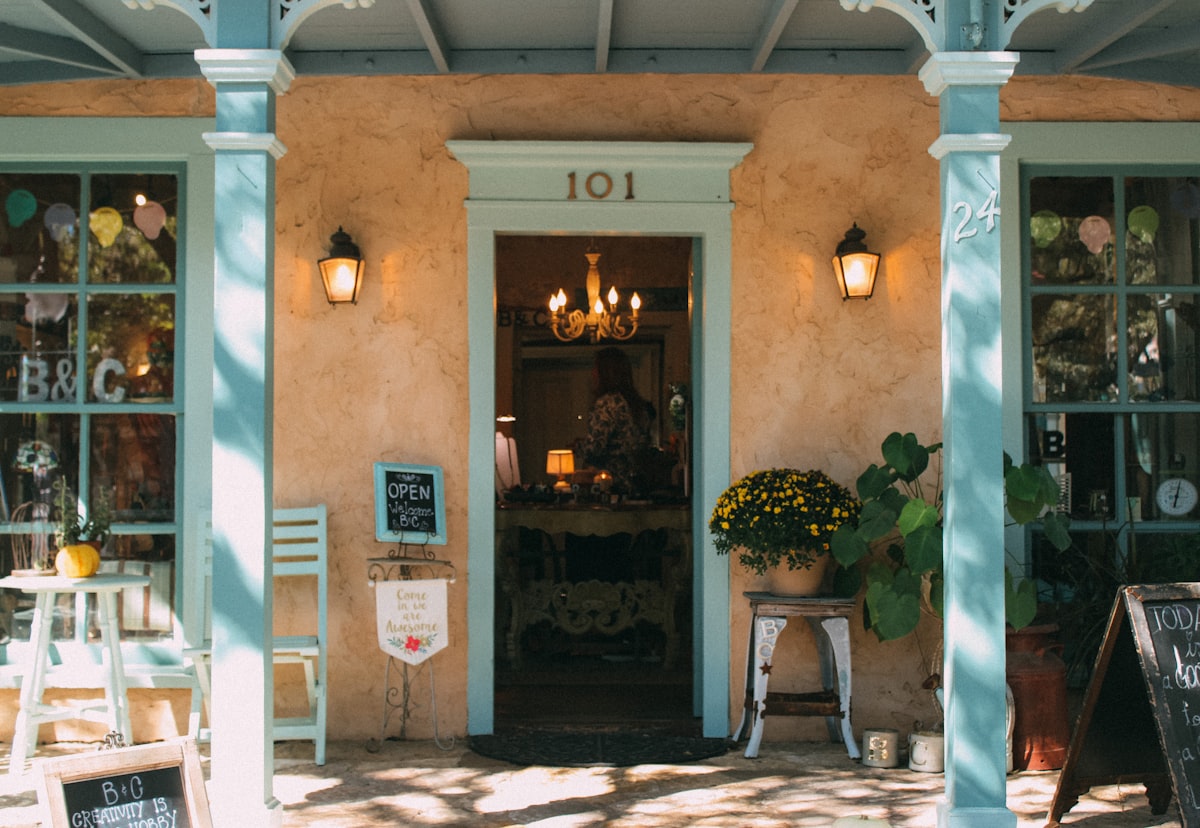 a building with a glass door and a table with chairs and plants related to Discover Cozy Charm in San Antonio: Bed and Breakfast Accommodations