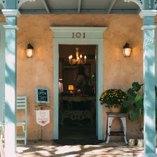 a building with a glass door and a table with chairs and plants related to Discover Cozy Charm in San Antonio: Bed and Breakfast Accommodations