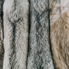 a bunch of fur coats hanging on a rack related to Faux Fur Coverlet: Luxurious Comfort for Your Home
