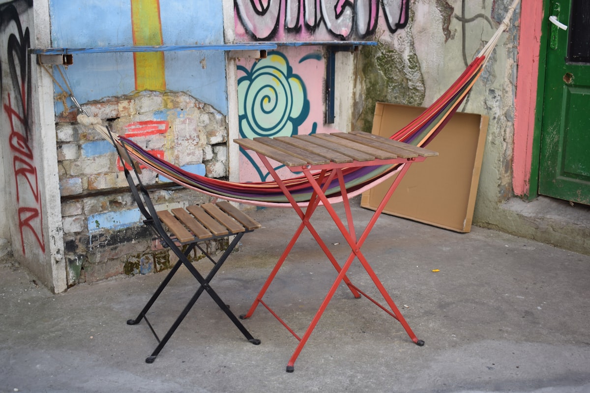 a chair and a table in front of a wall with graffiti related to Ultimate Comfort: The Indoor Hammock Bed with Stand