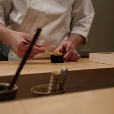 A chef prepares sushi on a wooden counter related to Master the Art of Sushi with a Sushi Making Kit from Bed Bath & Beyond