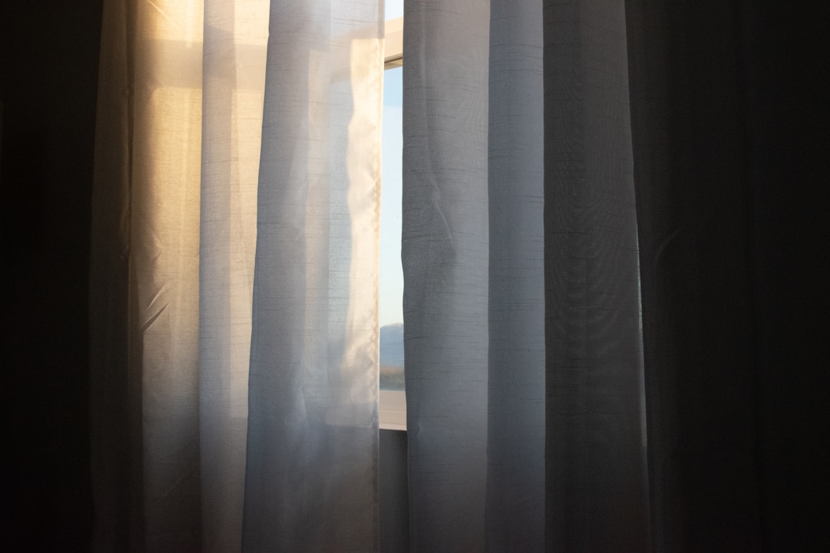 a close up of a curtain with a window in the background related to Window Treatments
