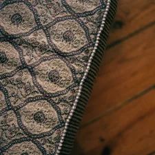 a close up of a rug on a wooden floor related to Scalloped Matelasse Coverlet: Stylish Bedding Solution