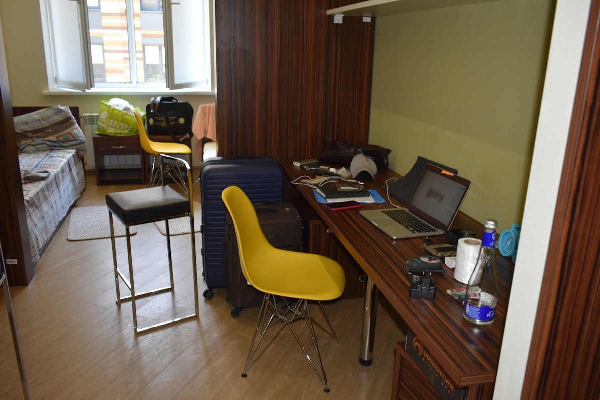 A cluttered room with a desk, chairs, and luggage. related to Essential Bed Bath and Beyond Dorm Checklist for a Smooth Move-In