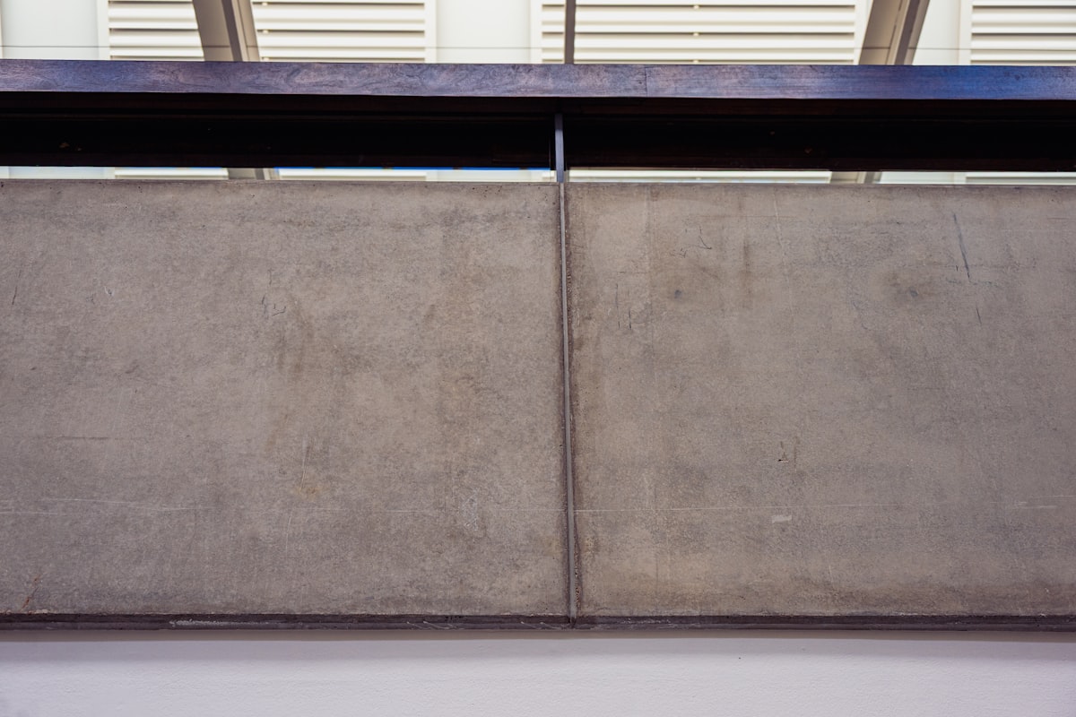 A concrete wall with a dark metal beam above. related to Graceful Elegance: Mirrored 4-Door Sideboard Statements