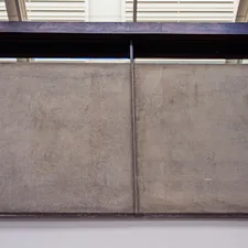 A concrete wall with a dark metal beam above. related to Graceful Elegance: Mirrored 4-Door Sideboard Statements