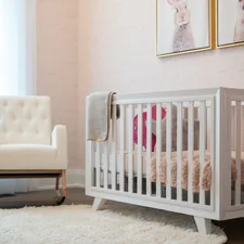 A cozy nursery with a white crib and armchair. related to Elevating Your Baby's Room with Adorable Valances