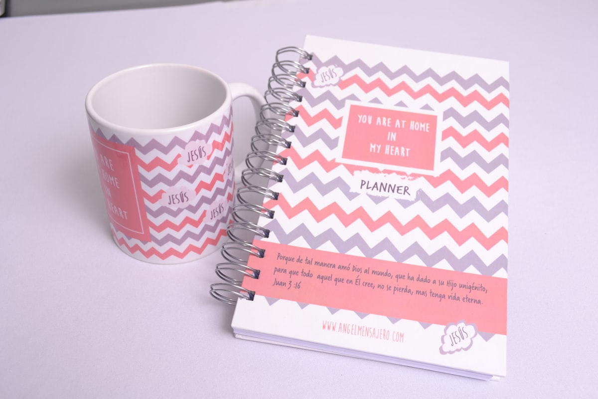 a cup of coffee next to a planner related to Pink and Grey Chevron Crib Bedding: A Stylish Nursery Must-Have