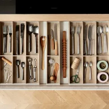 A cutlery drawer with wooden drawer inserts and black and silver cutlery. related to Maximizing Space: Innovative Storage Solutions for Small Entryways