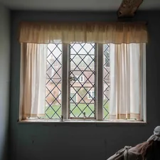 A diamond-paned window with sheer curtains overlooks a garden. related to 3 Inch Rod Pocket Valance: A Comprehensive Guide