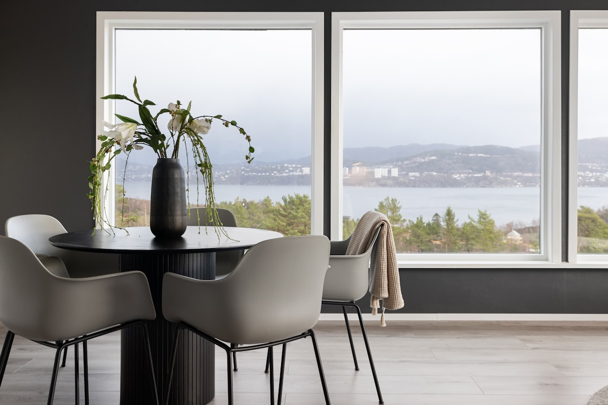 A dining room table with chairs and a vase of flowers related to Elevate Your Windows with Modern Curtain Valances