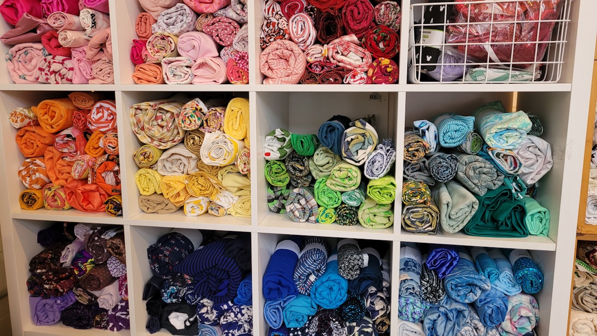 A display of quilting fabric, rolled into cylinders and sorted by color, stored in cube shelving. At Make & Mend, a used arts and crafts supply shop. related to How to Sew Valances