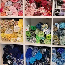 A display of quilting fabric, rolled into cylinders and sorted by color, stored in cube shelving. At Make & Mend, a used arts and crafts supply shop. related to How to Sew Valances