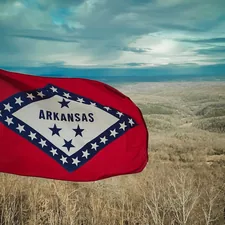 a flag in a field with a sky in the background related to Discover the Best Bed and Breakfasts in Arkansas