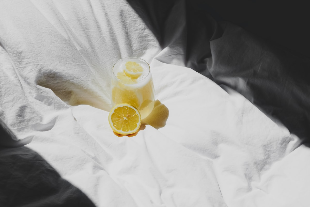 a glass of lemonade sitting on top of a bed related to The Ultimate Guide to Juicers at Bed Bath & Beyond: Everything You Need to Know