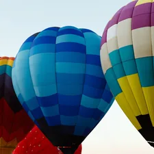 A group of colorful hot air balloons flying in the sky related to Elevate Your Nursery with Hot Air Balloon Baby Bedding
