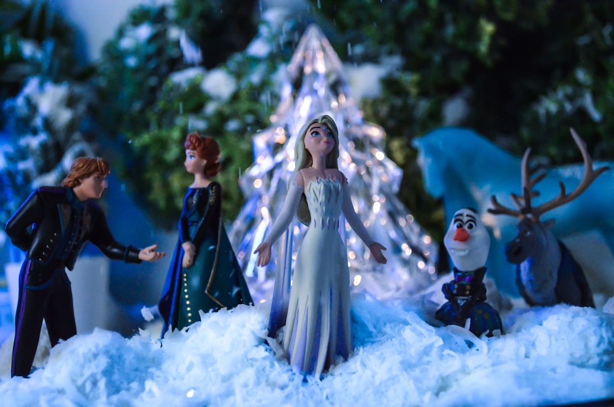 a group of figurines standing in front of a christmas tree related to Chilling Style: The Ultimate Guide to Frozen Crib Bedding